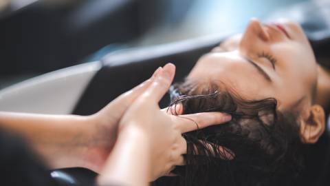 A photo of a lady having her hair washed at a salon, the barber's fingers massaging her scalp.