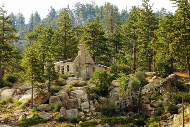A photo of the Dam Keepers house secluded by the dense forest, the boulders providing a natural retaining wall.