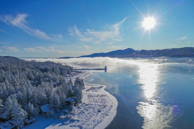 A photo of the Big Bear Lake during the winter, the snow covered ground and observatory visible in the distance.