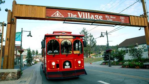 The Mountain Trolley driving underneath Big Bear's "The Village Sign"