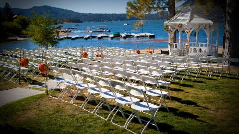 Rows of white chairs and a wedding alter under a gazebo sit lakeside in Big Bear Lake.