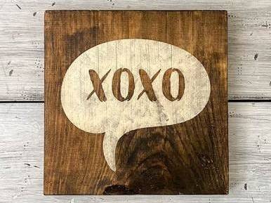एक लकड़ी का चिन्ह जिस पर XOXO लिखा है, सफेद पृष्ठभूमि पर रखा है।